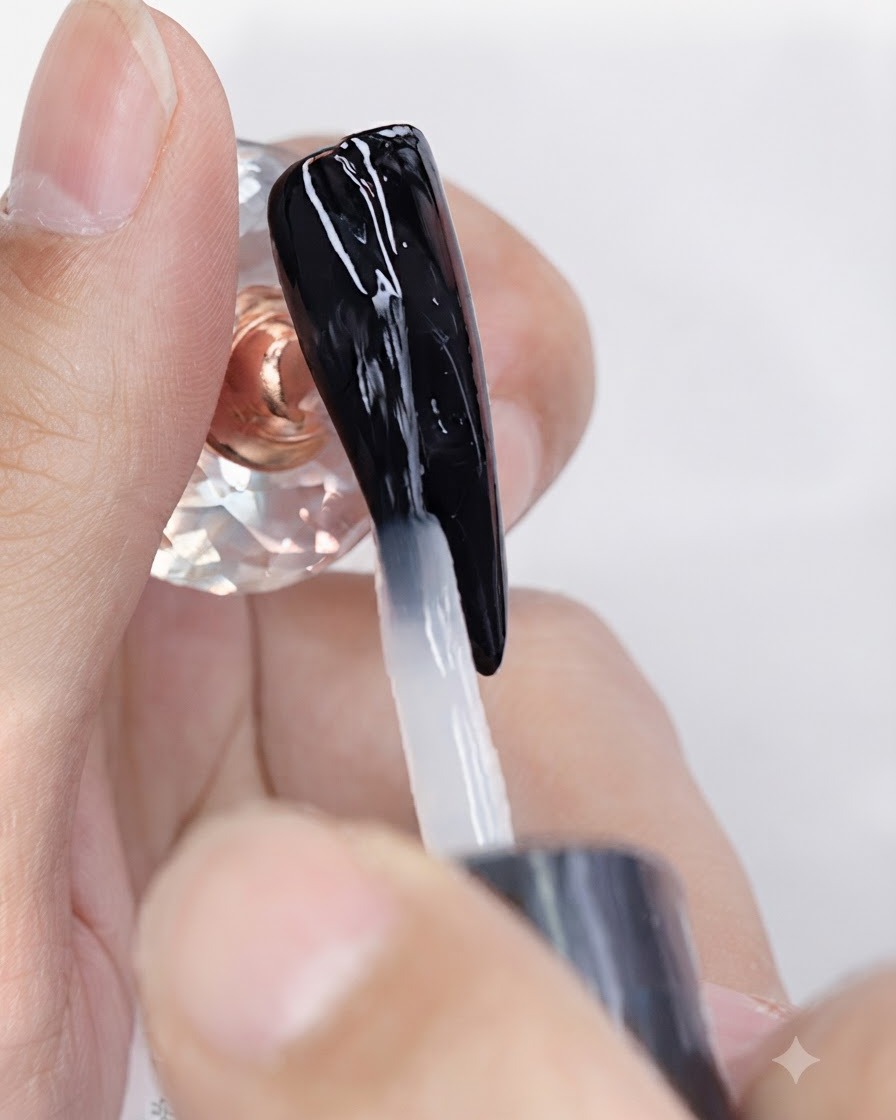 Un pinceau appliquant un top coat gel mat transparent sur un ongle vernis en noir.