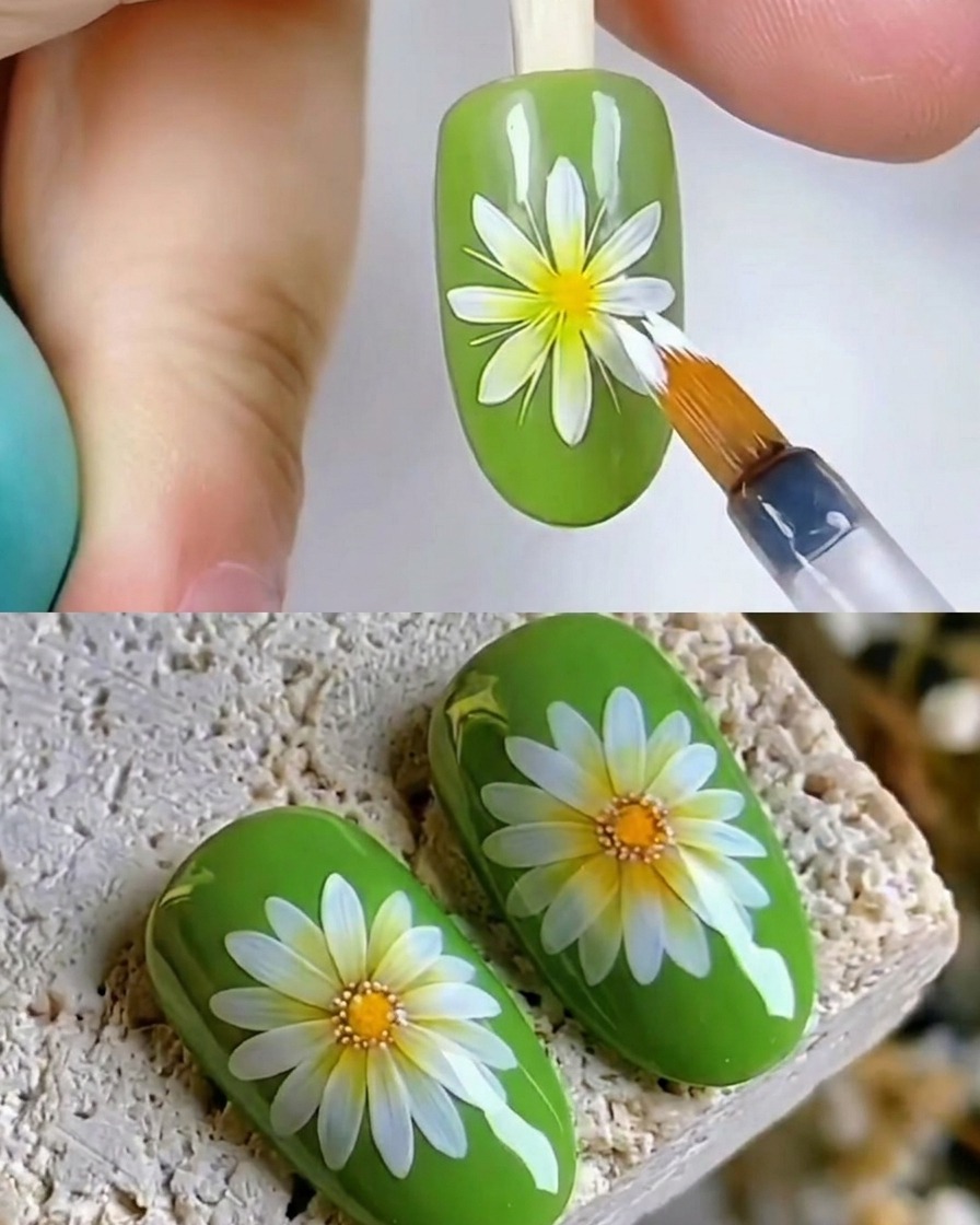 Gros plan dun pinceau appliquant un top coat transparent brillant sur un motif dongle marguerite blanche sur un ongle vert.