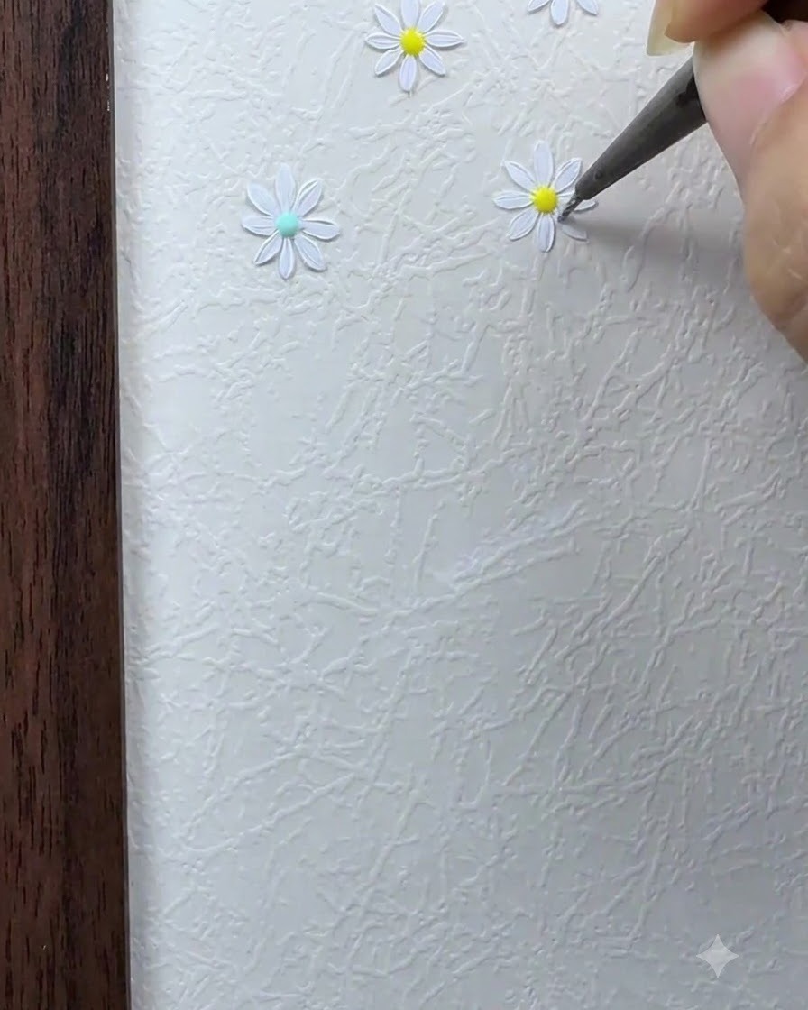 Un pinceau fin remplissant les pétales blancs restants autour du centre de la fleur de marguerite.