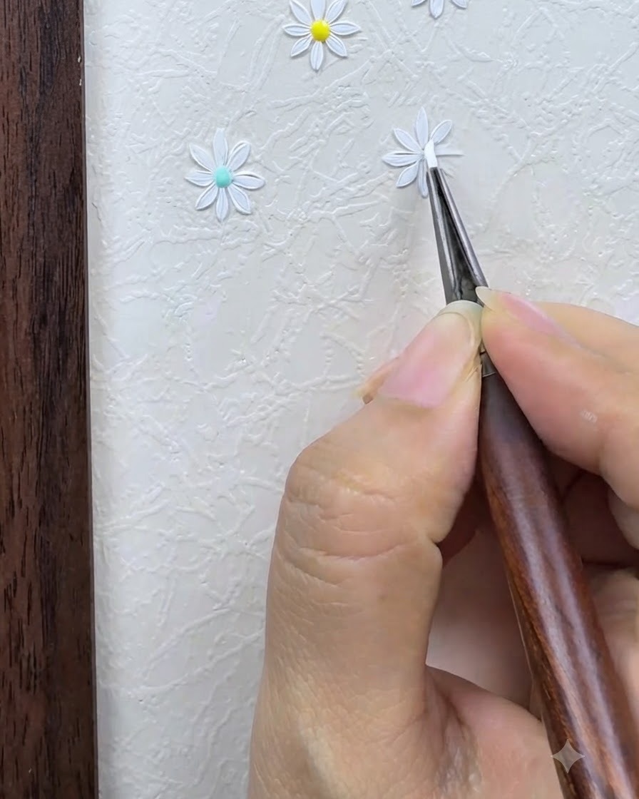 Un pinceau de détail dessinant et affinant soigneusement les pétales blancs dune marguerite peinte sur un fond de nail art texturé.