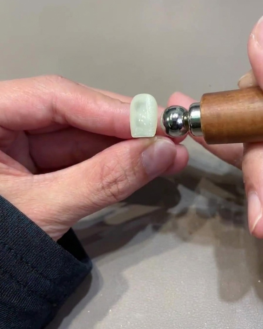 Un outil magnétique sphérique planant à côté dun ongle pour façonner le reflet cat-eye.