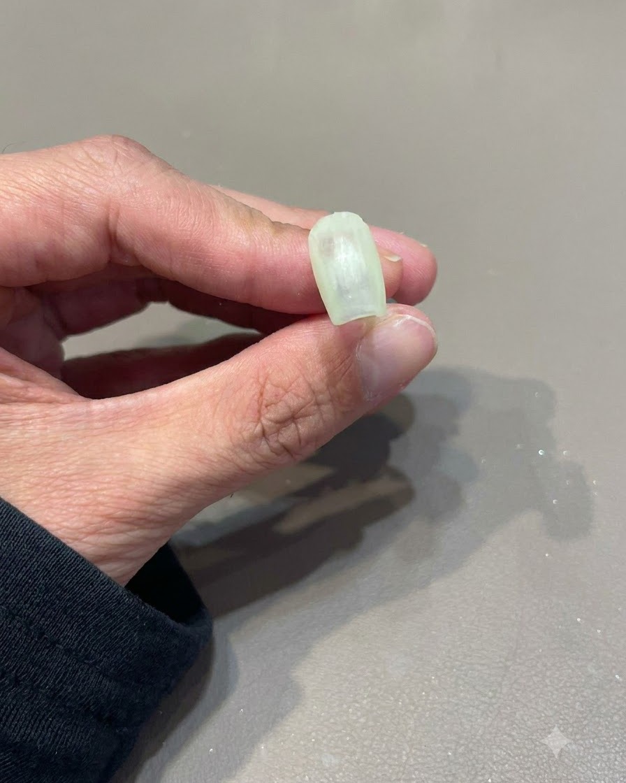 Une main essuyant la surface dun ongle catalysé avec un disque de coton.