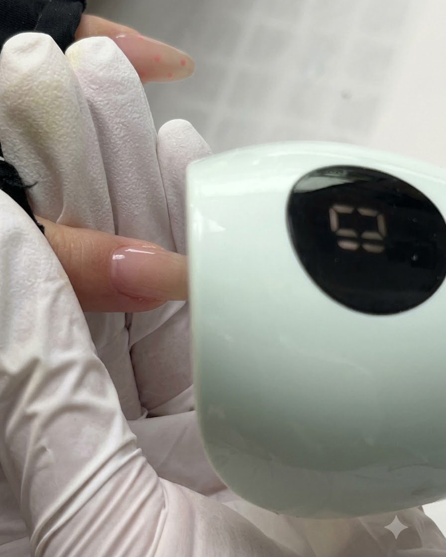 Un ongle catalysant sous une lampe UV/LED verte compacte affichant lécran du minuteur numérique.