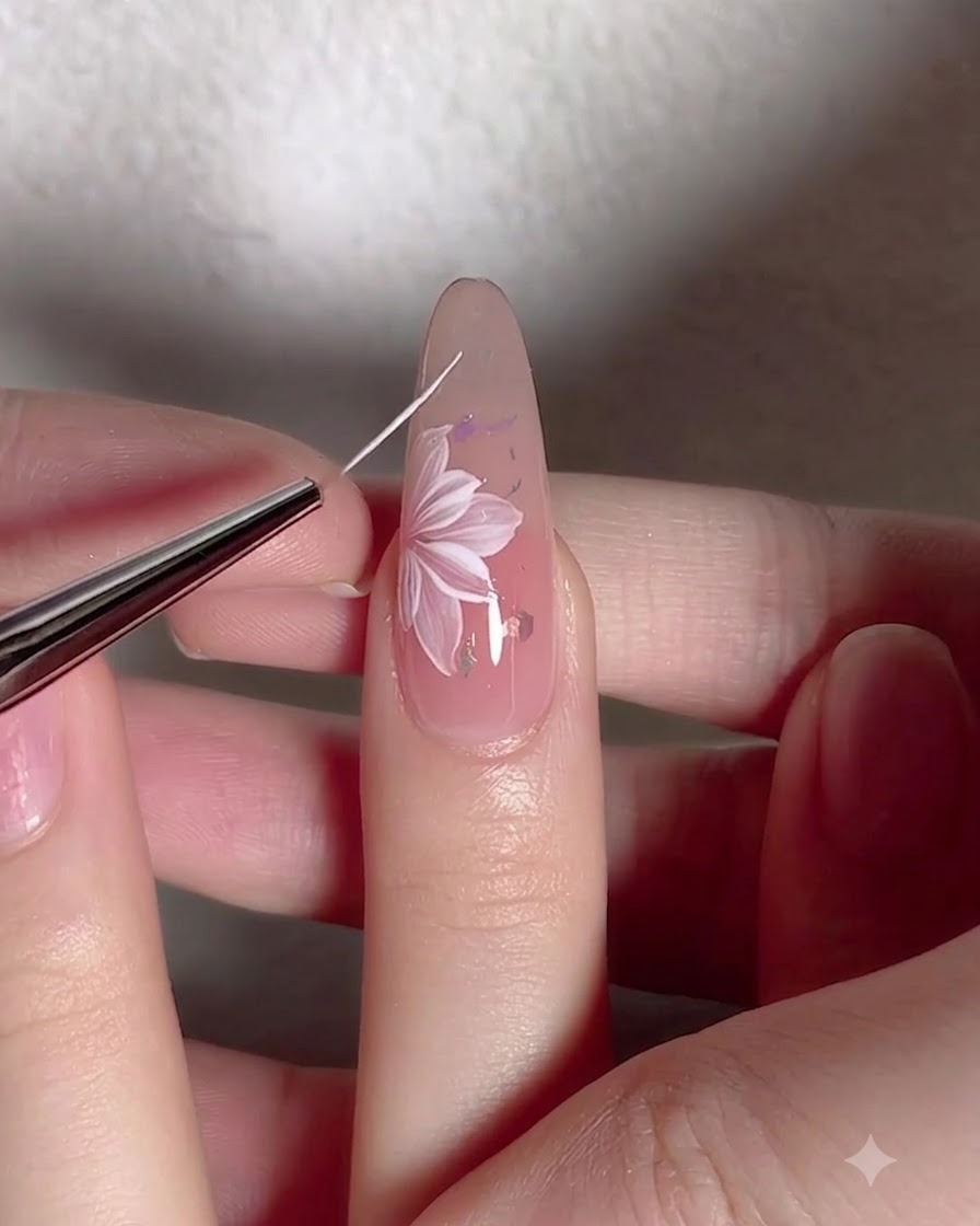Un pinceau liner fin dessinant de délicates lignes de tiges blanches autour dune fleur peinte sur un ongle.
