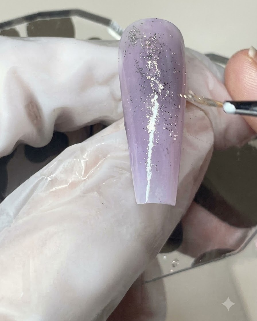 Un pinceau à gel appliquant une couche uniforme de finition mate sur un ongle dégradé violet infusé de paillettes.