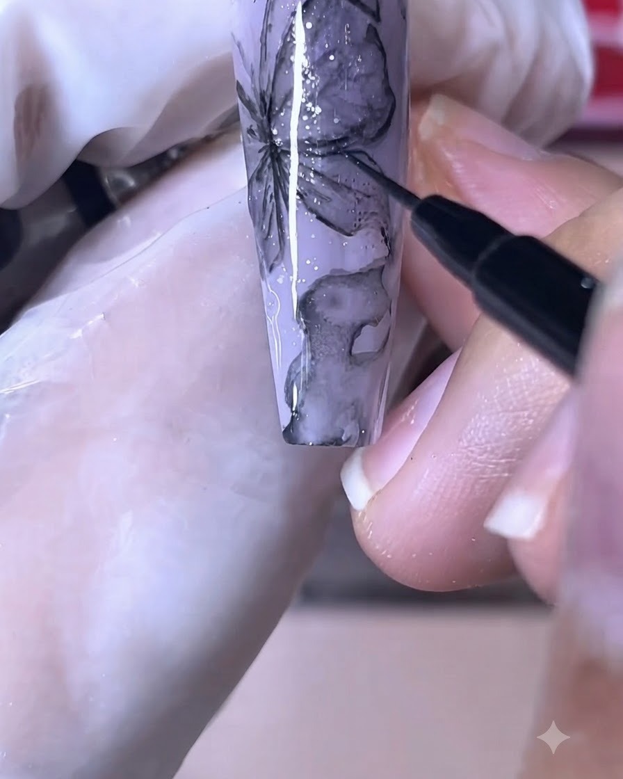Un pinceau à ongle fin dessinant des lignes noires nettes sur un design dongle papillon violet.