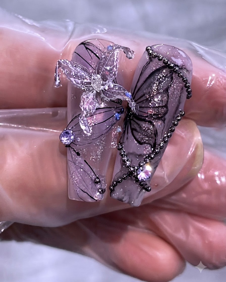 Gros plan dun ensemble fini de designs de nail art papillon et chaîne violet sur de longs faux ongles transparents.