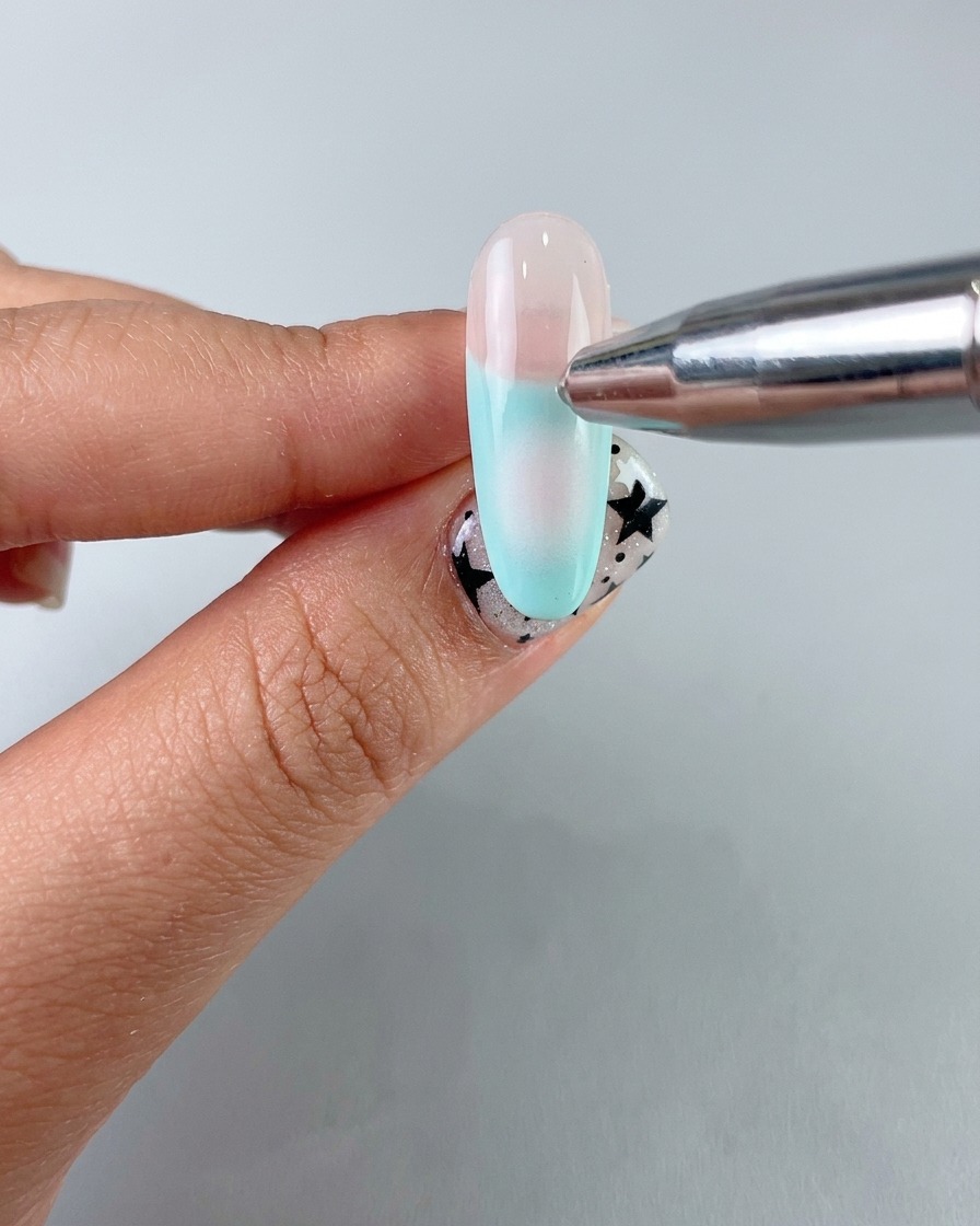 Un applicateur éponge appliquant un doux dégradé blush au centre avec un gel délicat sur longle.