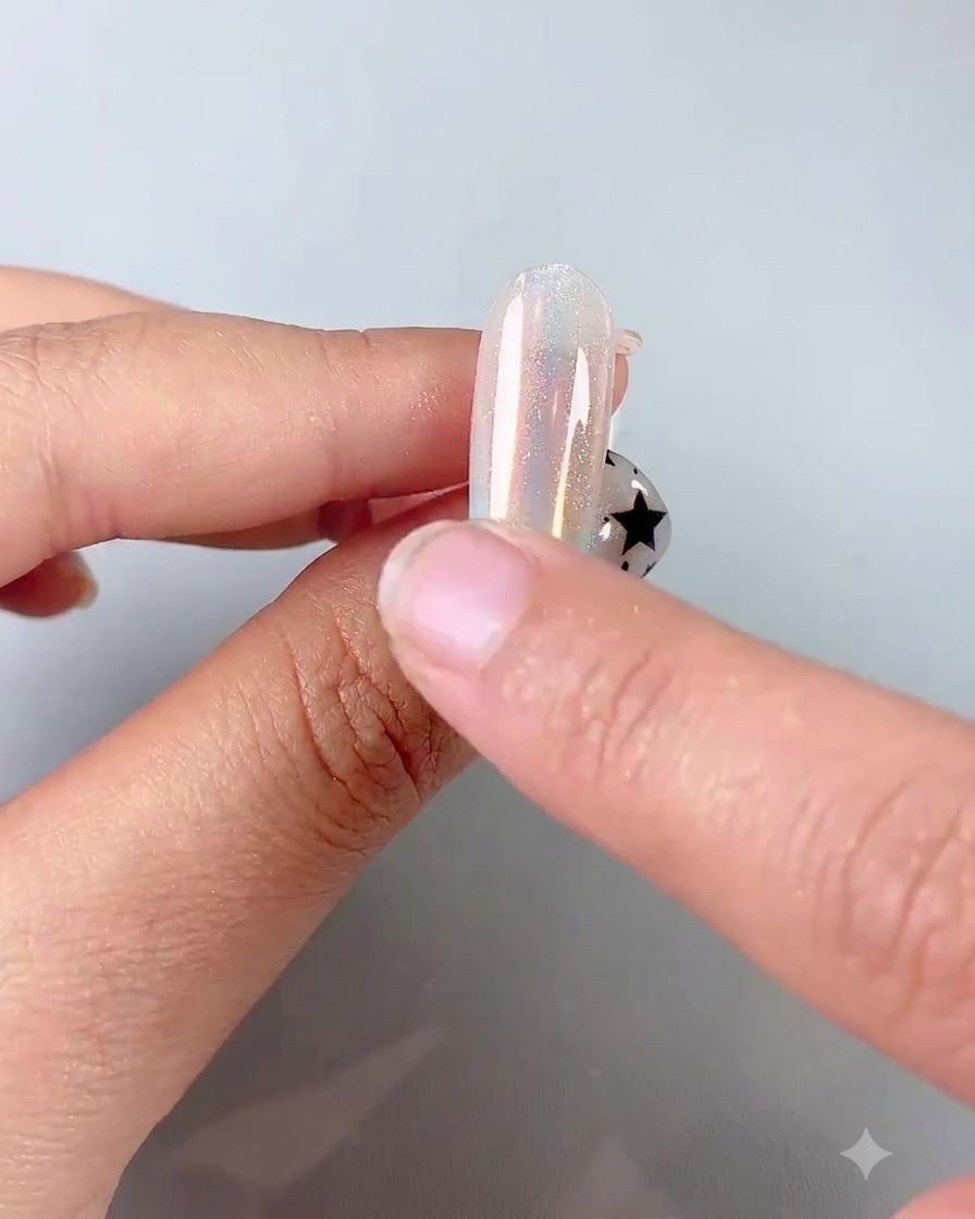 Un doigt utilisant un applicateur éponge en silicone pour frotter la poudre chrome irisée sur un ongle brillant.