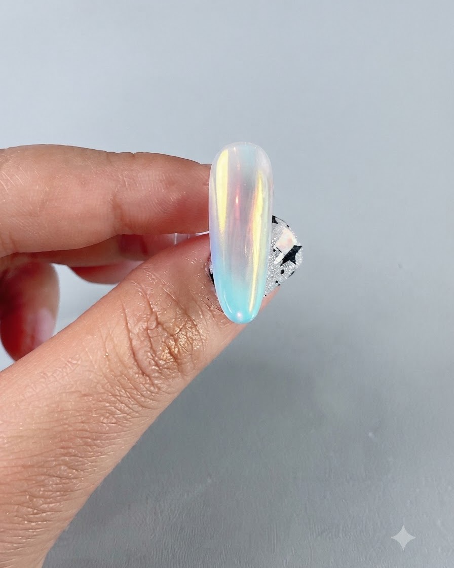 Gros plan dun ongle chrome aurora irisé et terminé montrant un reflet miroir multicolore vibrant.