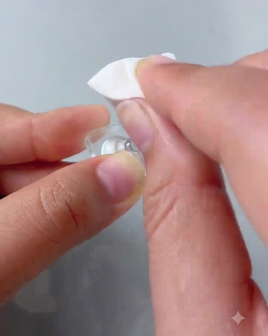 Un applicateur éponge tamponnant du vernis gel rose sur le bout dun ongle dentraînement transparent.