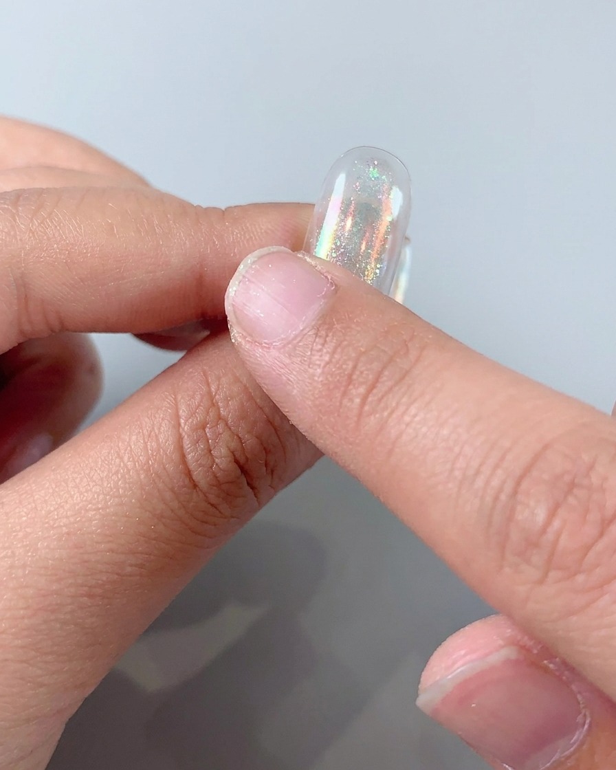 Frottement de poudre aurora holographique sur un ongle pour créer une finition métallique brillante.