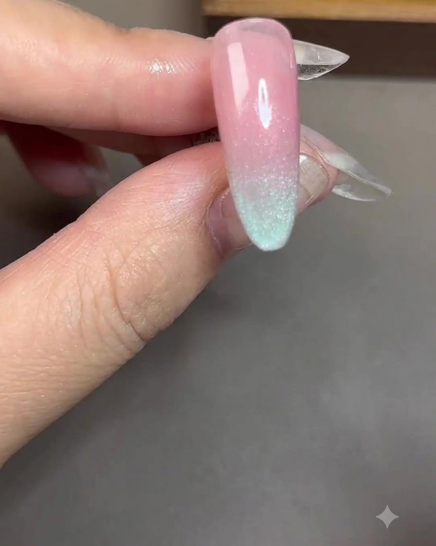 Un aimant cylindrique tenu près et parallèlement à un ongle recouvert de gel cat-eye bleu.