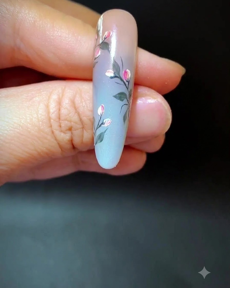 Un ongle présentant un nail art floral complété par de longues lignes fines et aériennes dans lespace dégradé.
