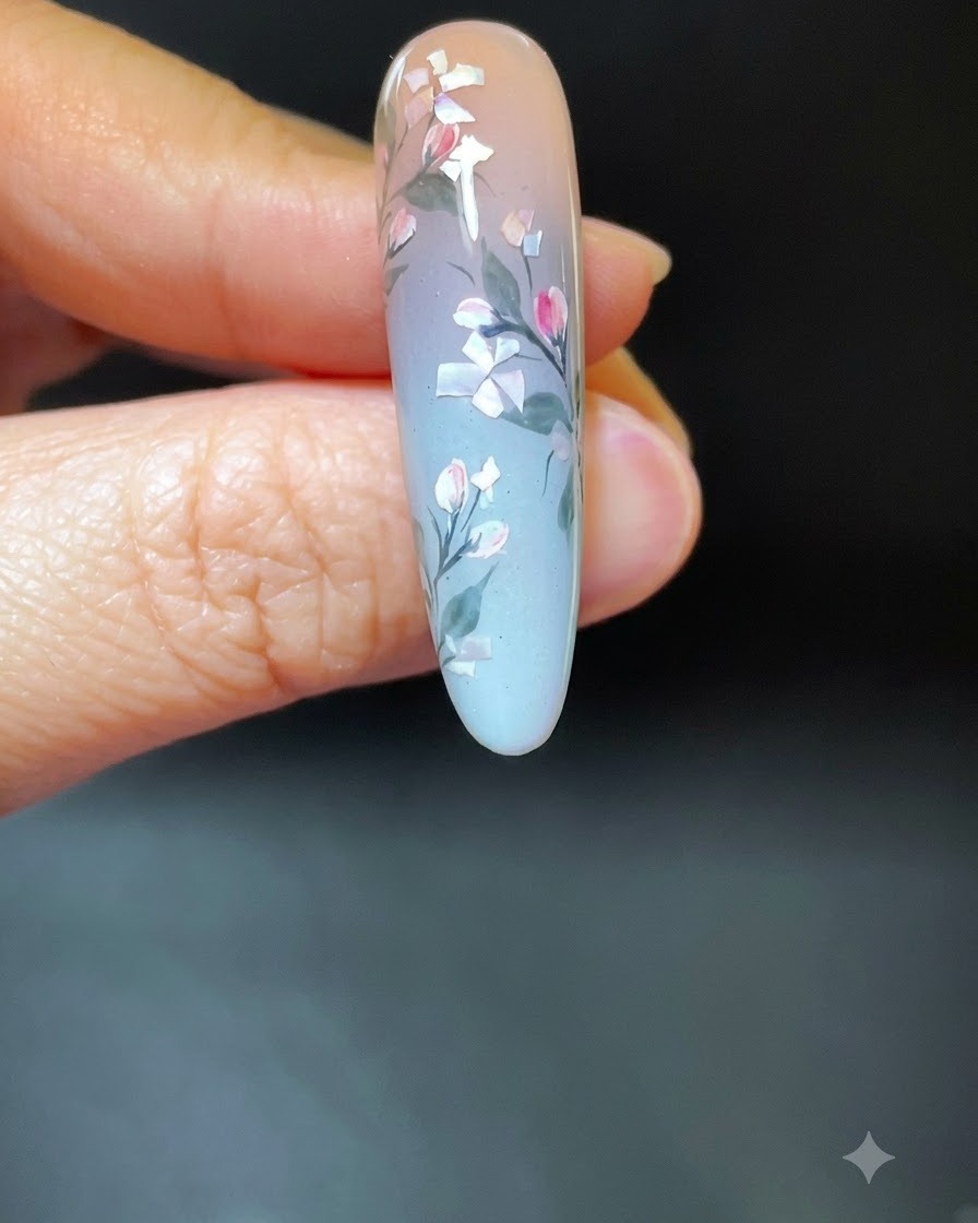 Une main portant un nail art floral en coquillage placée à lintérieur dune lampe UV/LED blanche.