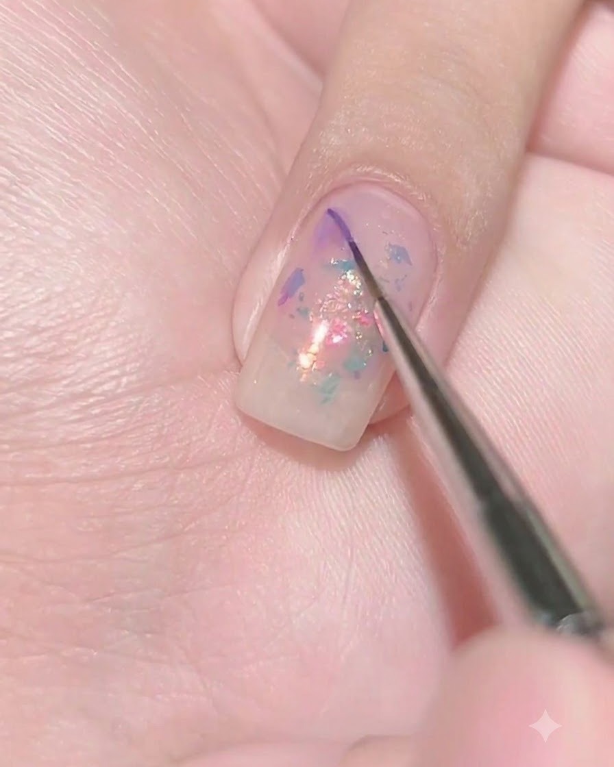 Un pinceau fin déposant une minuscule goutte de gel violet foncé sur la surface humide dun ongle violet diaphane.