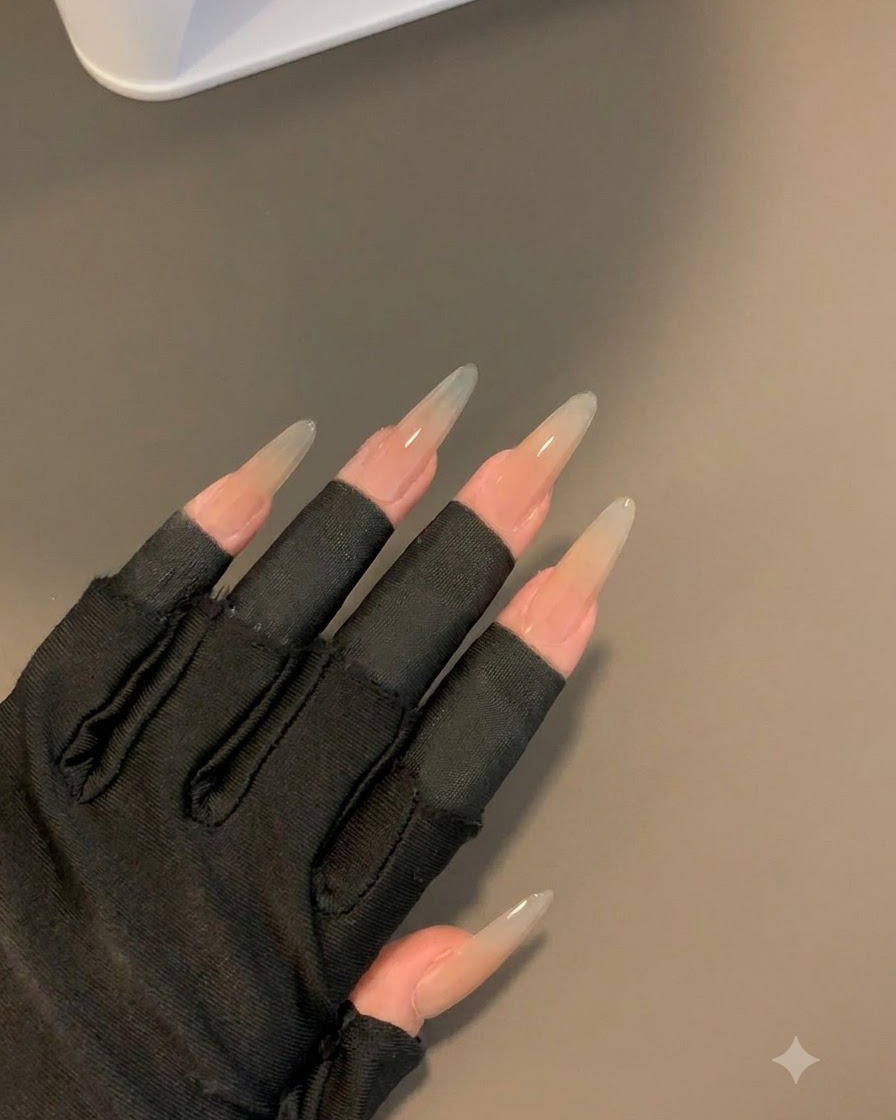 Une main gantée portant des manches noires sans doigts affichant les ongles catalysés après 30 secondes sous une lampe.