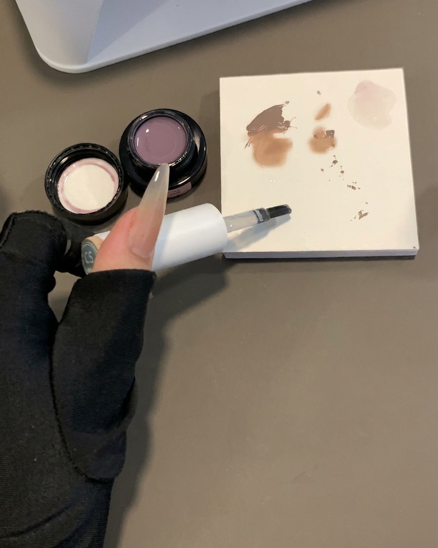 Un pinceau gel trempé dans du gel de base transparent à côté dune palette de mélange avec des échantillons de pigments.