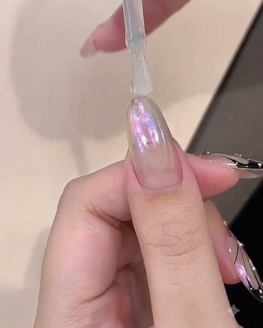 Un pinceau appliquant une couche claire de gel de construction sur un ongle au fini chrome.