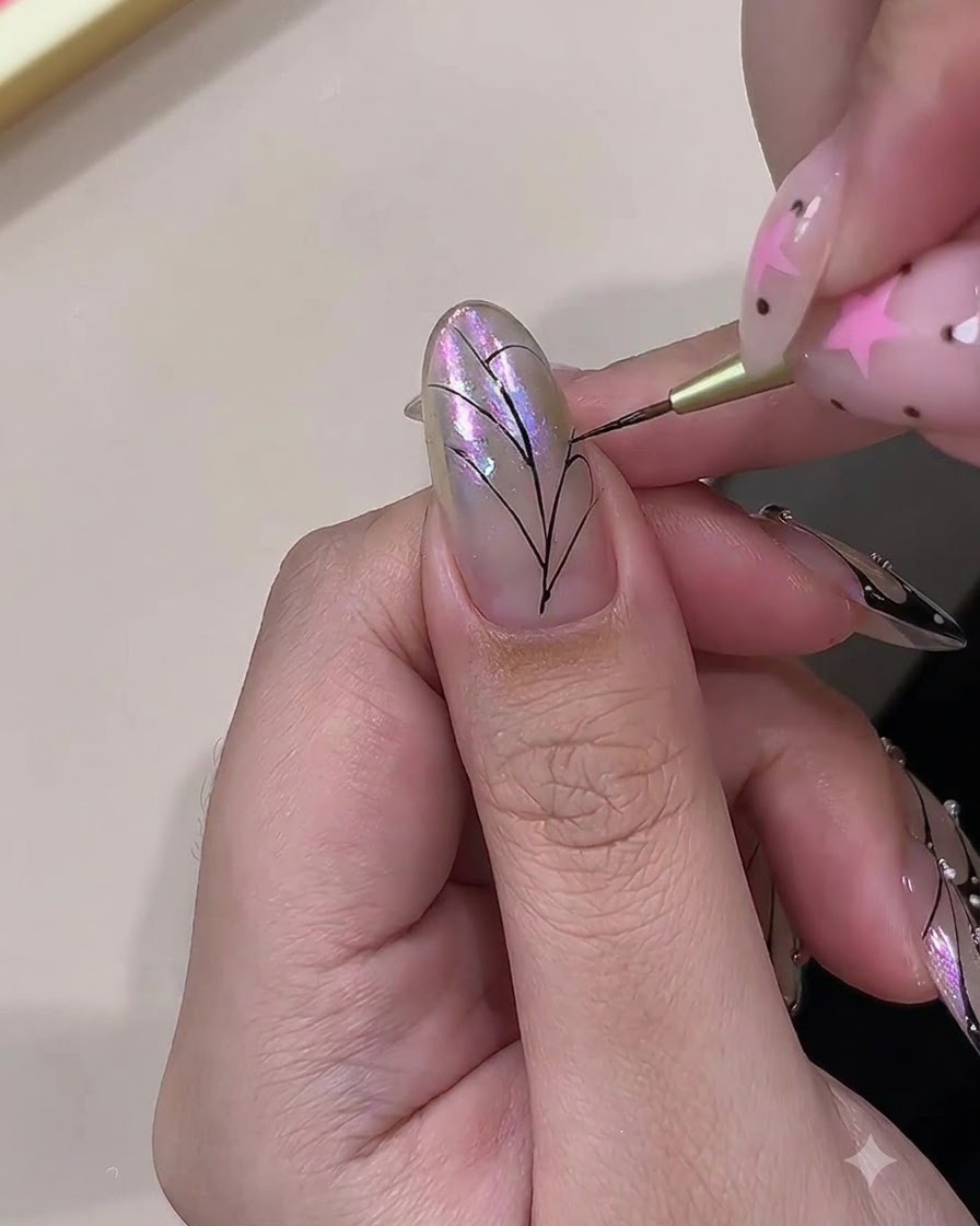 Un pinceau fin peignant des lignes noires incurvées pour connecter les nervures dun motif daile de papillon sur un ongle.
