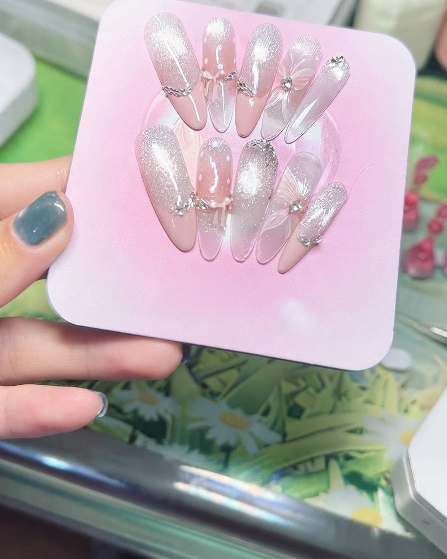 Une main inclinant un présentoir rose pour montrer les particules scintillantes de lœil de chat magnétique captant la lumière.