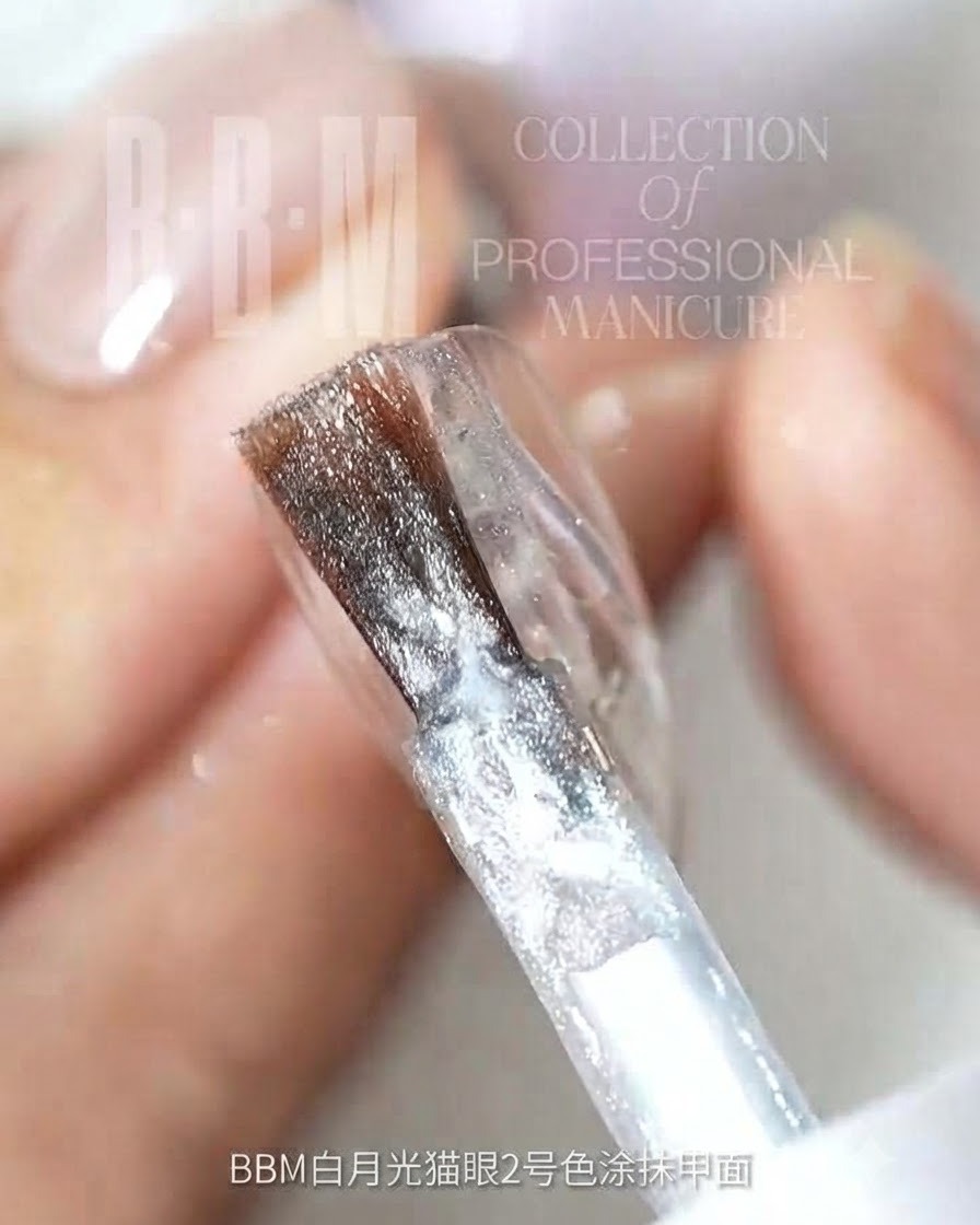 Un pinceau à ongles appliquant du gel cat-eye pailleté argenté sur une surface dongle transparente.