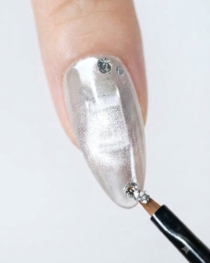 Un pinceau fin liner appliquant des paillettes argentées sur le bord dun ongle fini.