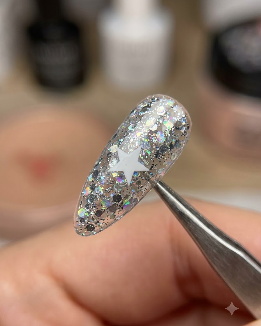 Une paire de brucelles soulevant un autocollant détoile blanche dun ongle pailleté scintillant.
