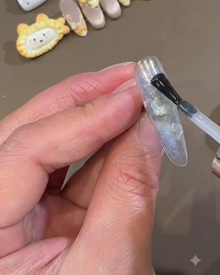 Un pinceau à vernis appliquant une couche lisse de top coat transparent sur un ongle press-on bleu glacial encapsulé.