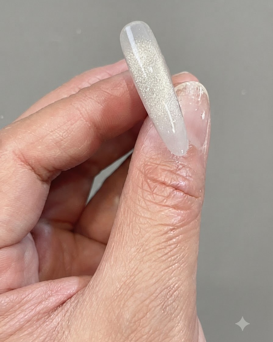 Une main tenant une capsule dongle transparente présentant un dégradé vertical chatoyant fait de gel de diamants brisés réfléchissants.