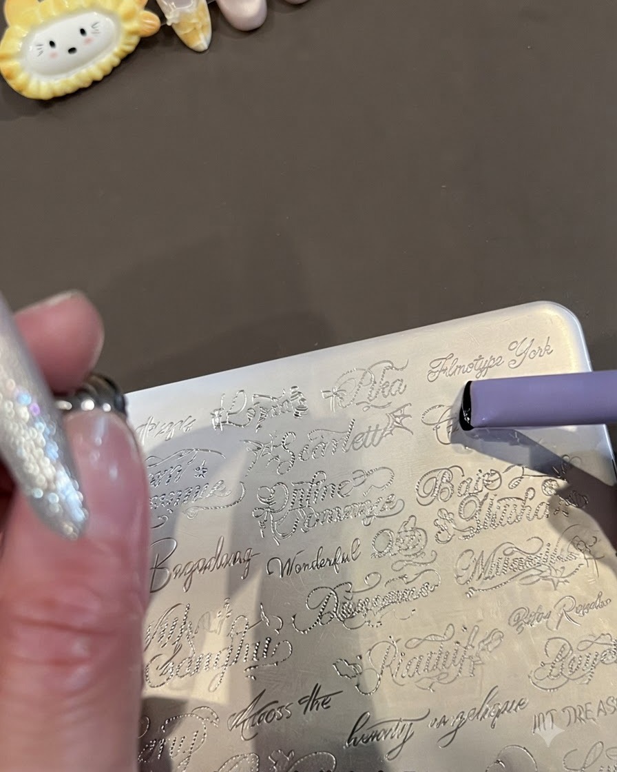 Gros plan dune plaque destampage en métal gravée de mots anglais cursifs et dun tampon en gelée violet ramassant le design.