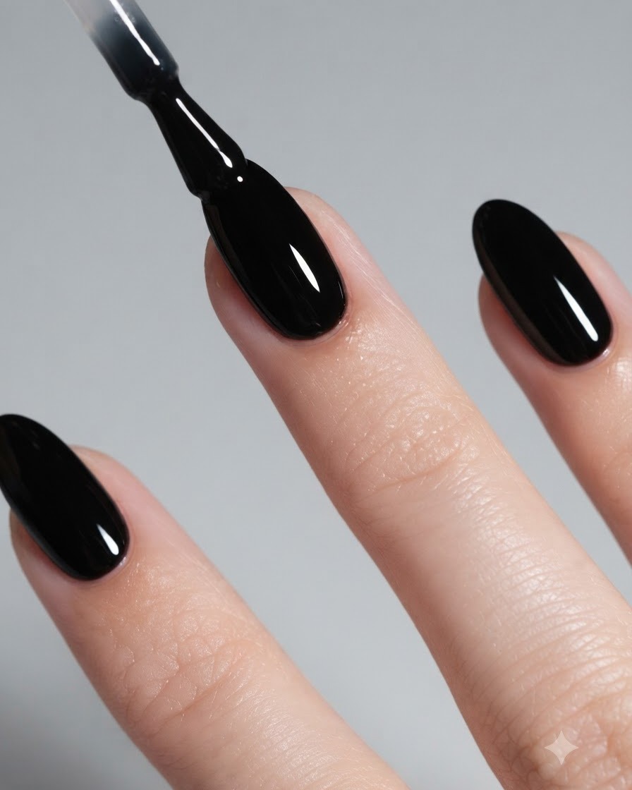 Gros plan dun pinceau appliquant du vernis gel noir brillant sur un ongle en forme damande.