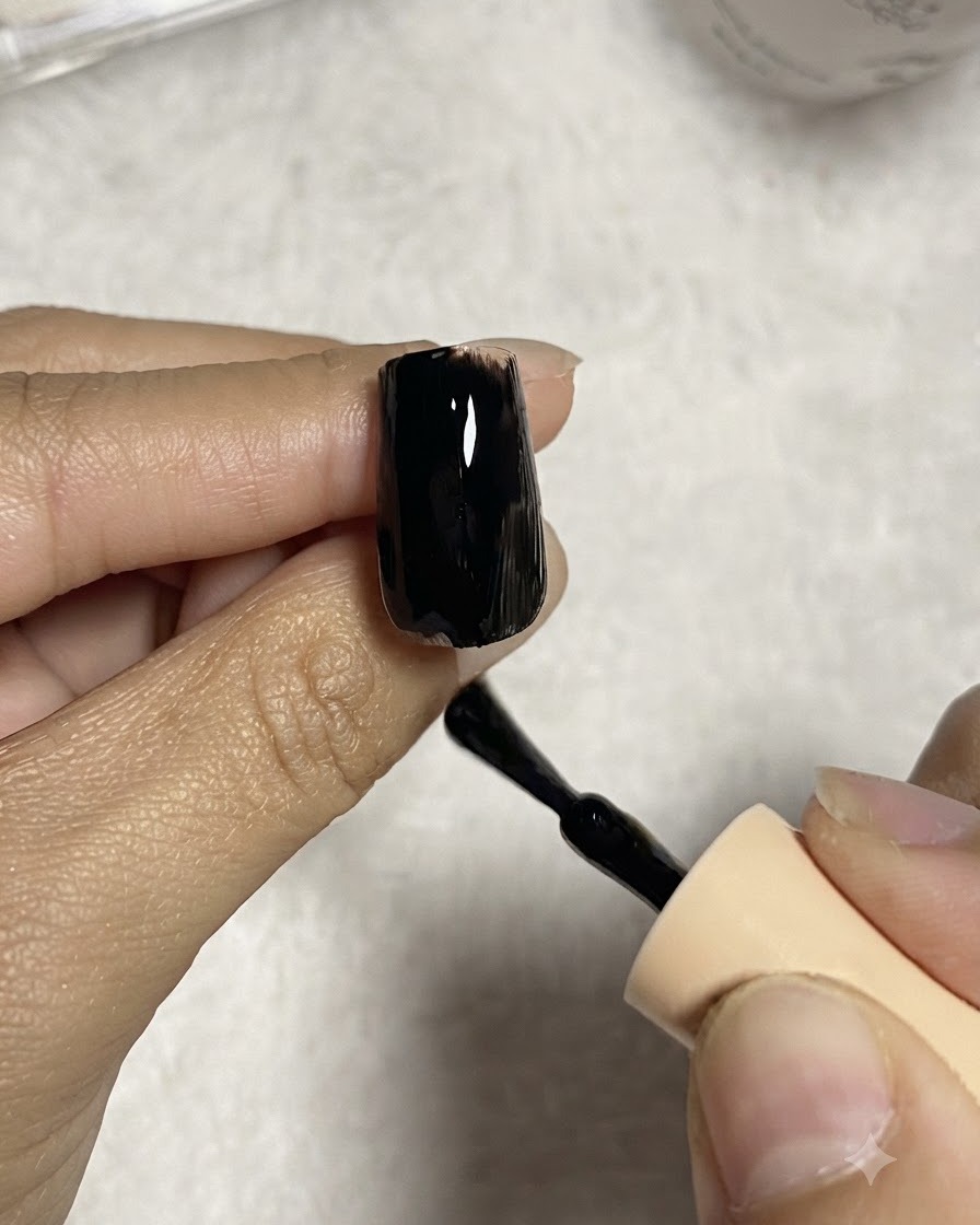 Un pinceau à ongles appliquant une couche lisse de vernis gel noir sur une capsule dongle transparente.