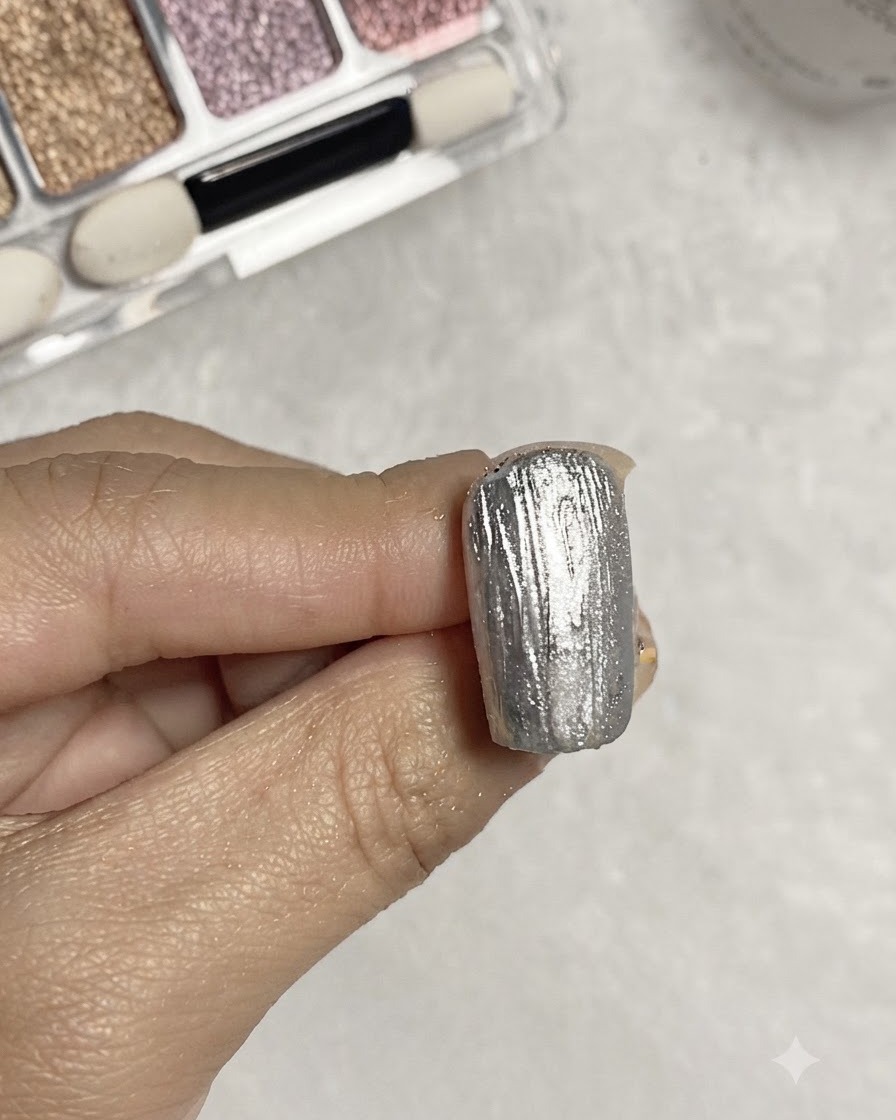 Un pinceau appliquant du gel de base transparent sur une surface dongle métallique texturée argentée.