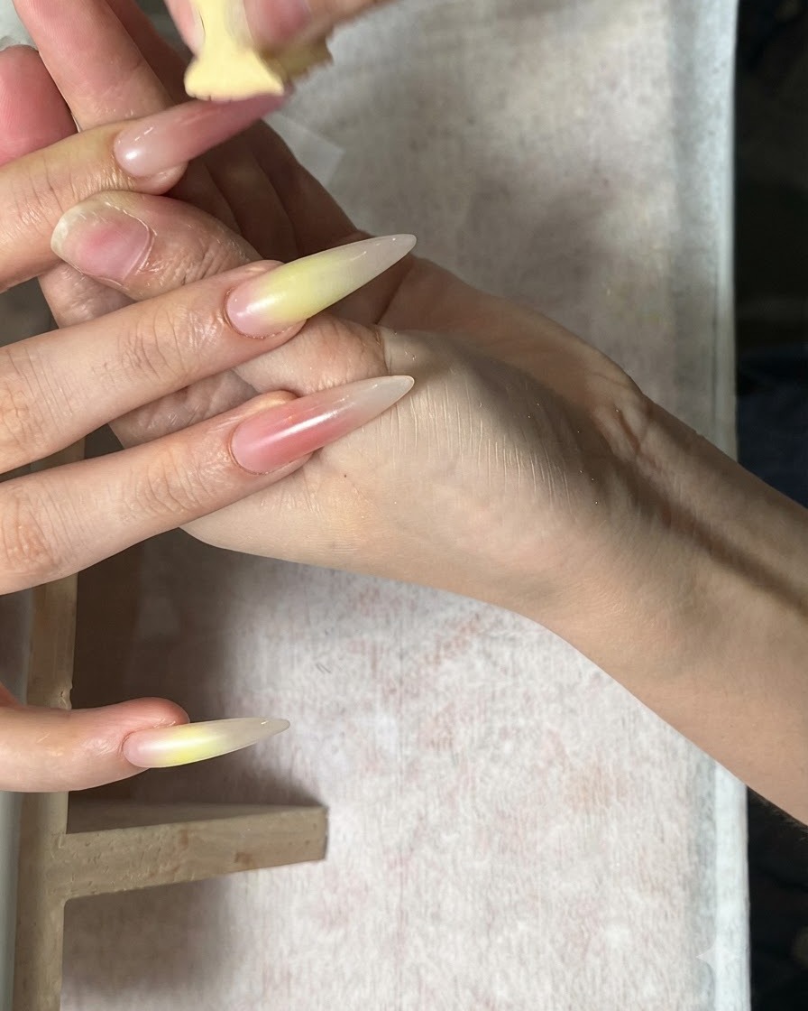 Mélange de tons vert et rouge corail à léponge sur des ongles en amande.