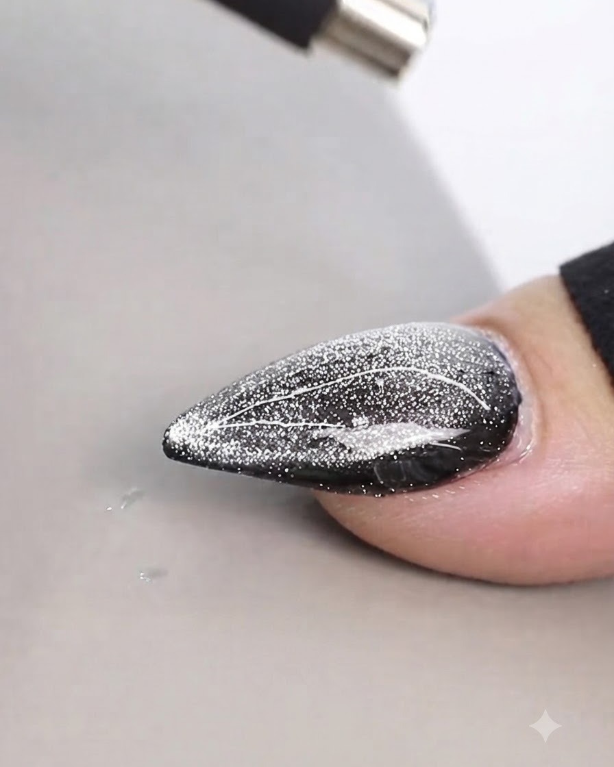 Un aimant cylindrique tenu de près au-dessus dun design dongle cat-eye scintillant pour créer des lignes fines.