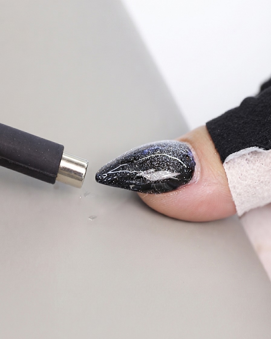 Un outil aimanté noir de type stylo approché près dune surface dongle cat-eye texturée.