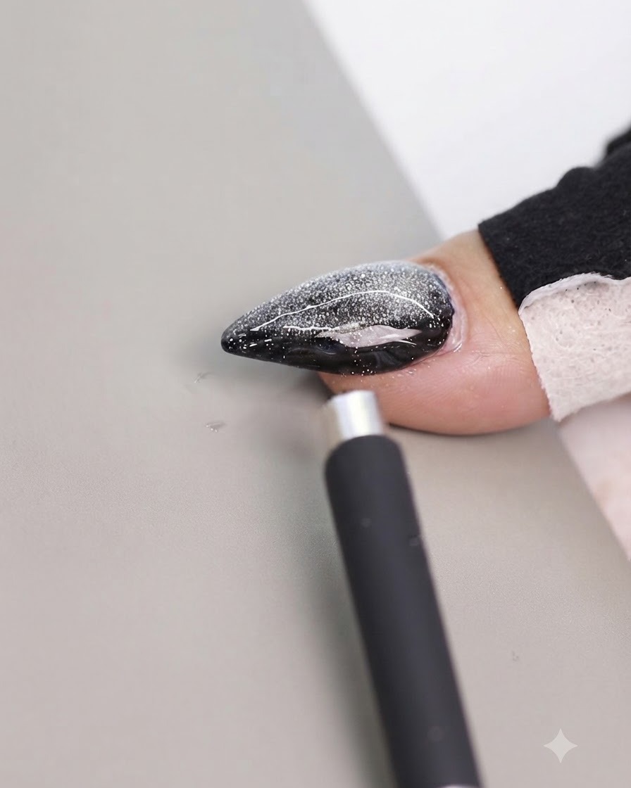 Un outil aimanté positionné près du bord latéral dun ongle cat-eye décoré pour déplacer le reflet.