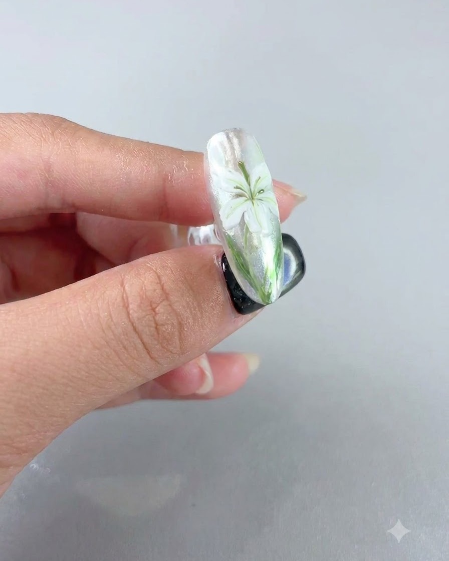 Un ongle parachevé affichant un design de lys blanc sous une couche de scellement mate veloutée.
