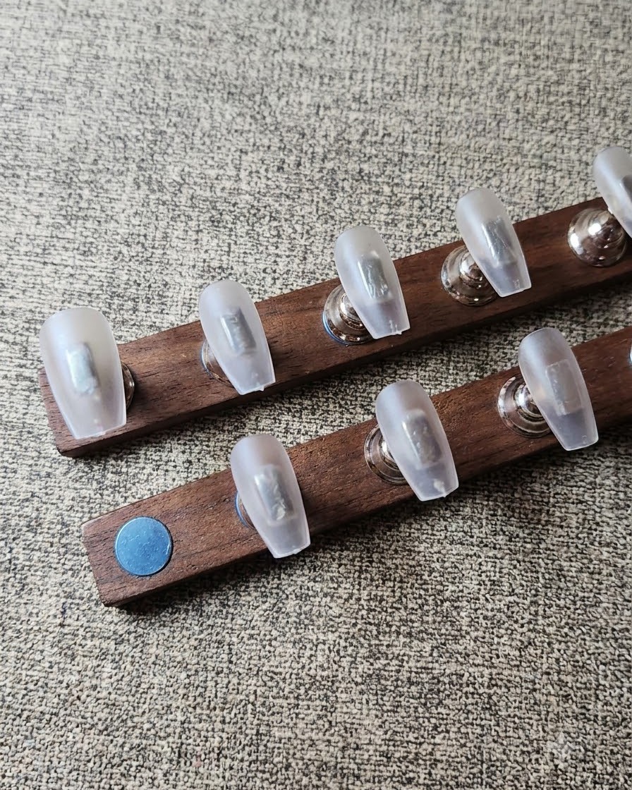 Une lingette non pelucheuse nettoyant la poussière sur des capsules dongles transparentes préparées et disposées sur un support en bois.