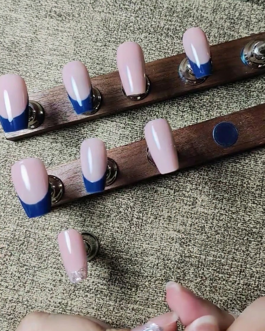 Un outil de pose plaquant de petits strass transparents sur une ligne de gel pailleté argenté encore humide.