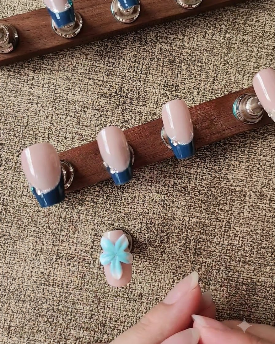 Un outil de modelage en silicone façonnant un pétale de fleur 3D blanc sur un faux-ongle.