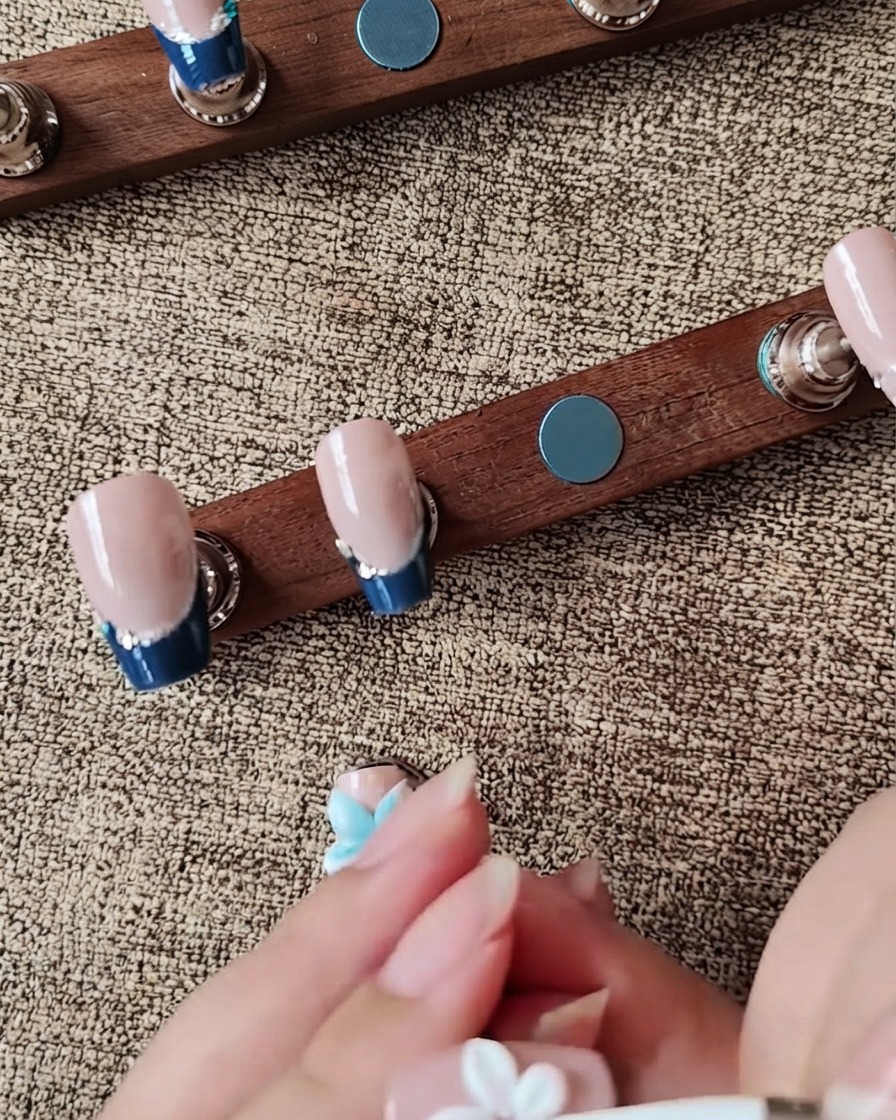 Un outil en silicone façonnant un pétale de fleur en gel 3D blanc sur un faux-ongle.