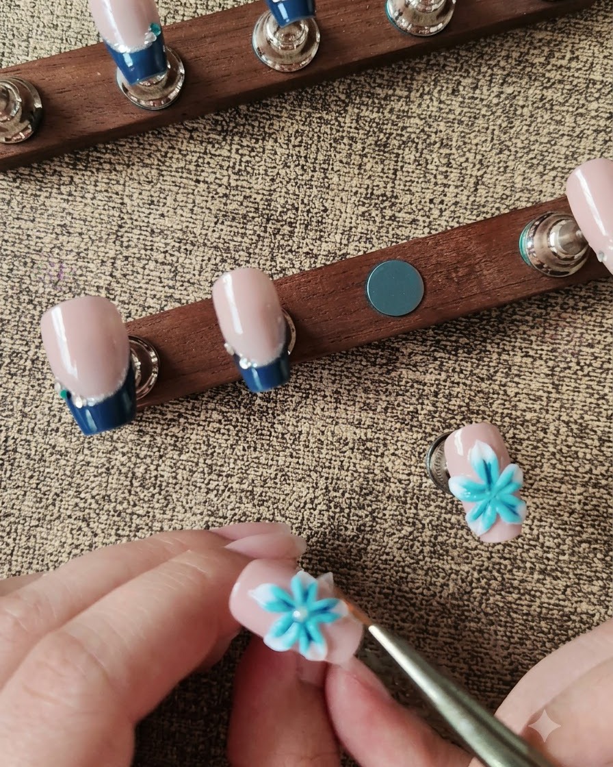 Un stylo à cire positionnant une perle blanche au centre dune fleur dongle 3D bleue et blanche.