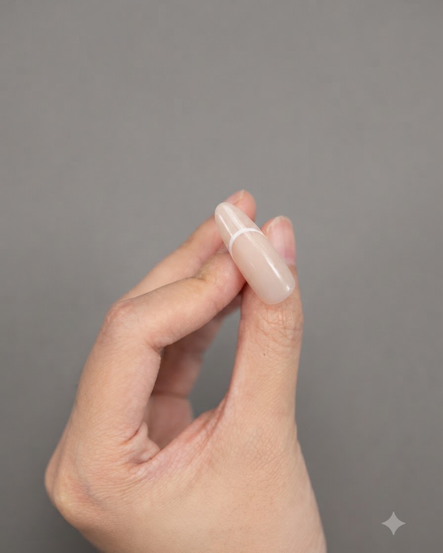 Des doigts tenant un ongle en forme damande présentant un design de French manucure blanc uni et complet.