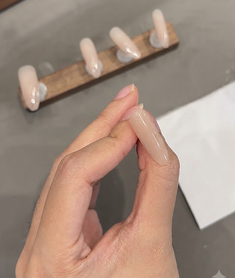 Une vue rapprochée dun ongle en amande montrant des lignes fines blanches précises peintes près de la zone des cuticules.