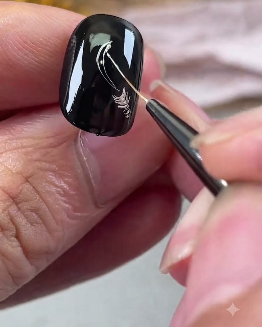 Un pinceau fin dessinant des contours de pétales argentés métalliques sur un ongle en gel noir.