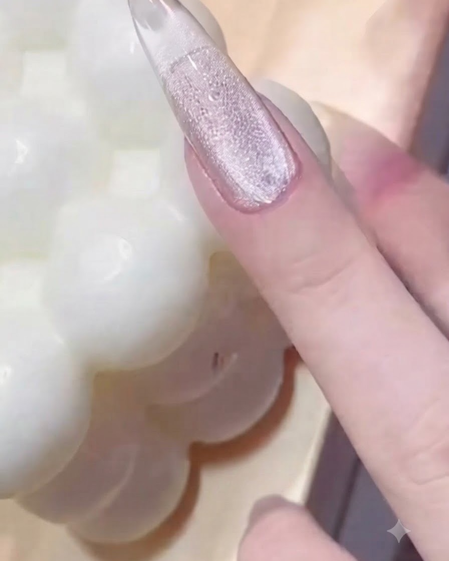 Une main pressant un outil annulaire à billes métalliques sur un ongle verni et brillant pour créer des empreintes texturées.