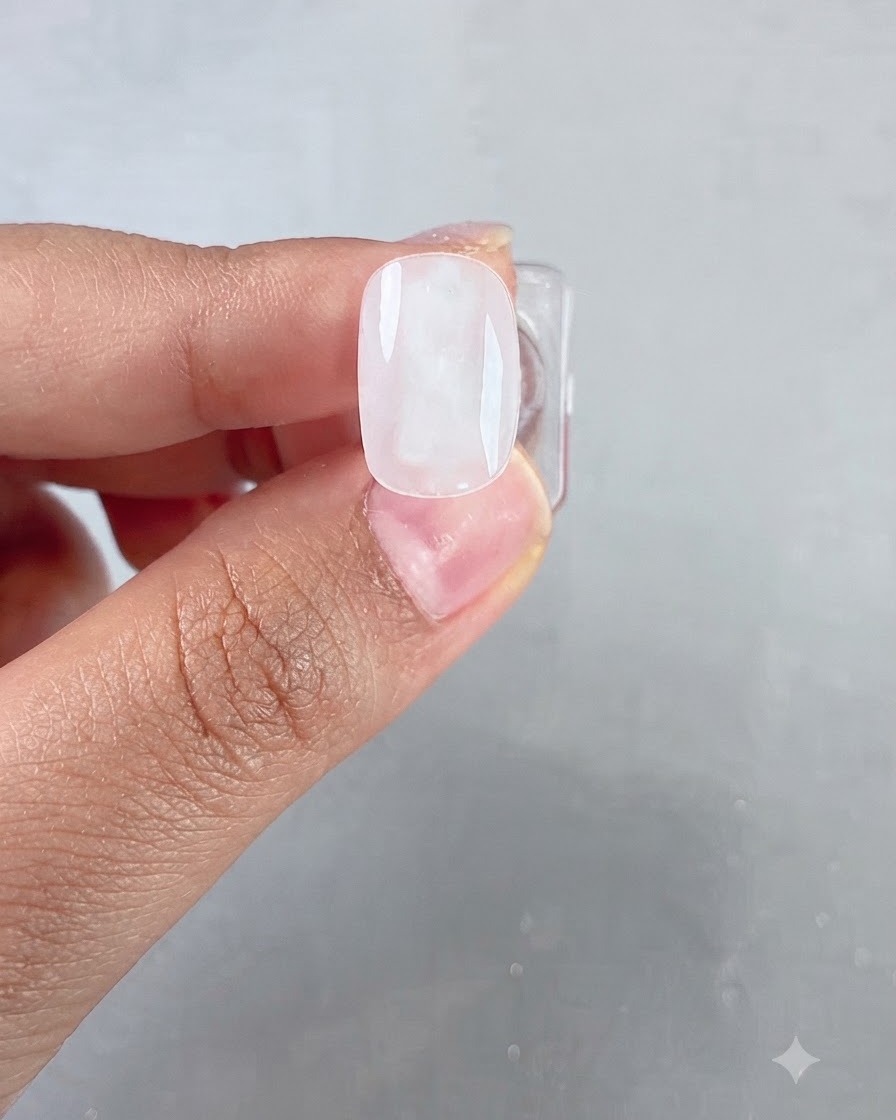 Gros plan dun pinceau appliquant une couche de gel transparent et brillant sur une base dongle blanc laiteux.