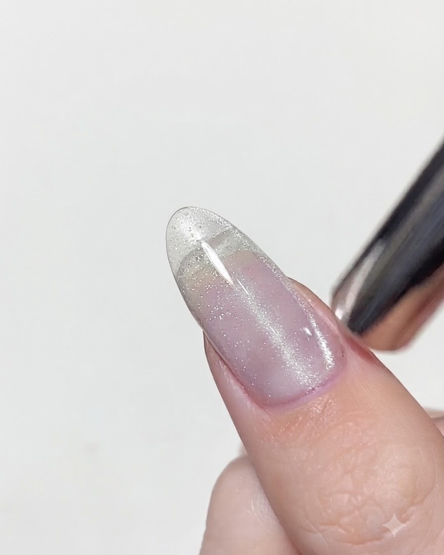 Un outil aimanté positionné tout près dun ongle vernis en gel œil de chat humide pour concentrer les reflets argentés en une ligne verticale.